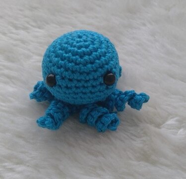 Kleiner türkisfarbener gehäkelter Oktopus mit schwarzen Augen
