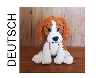 Gehäkelter braun-weißer Amigurumi-Hund mit Schlappohren, sitzend