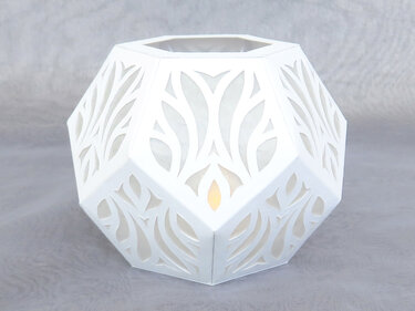 Kunstvoll gefaltete weiße Papierlaterne mit botanisch wirkenden Ausschnitten und leuchtendem Inneren.