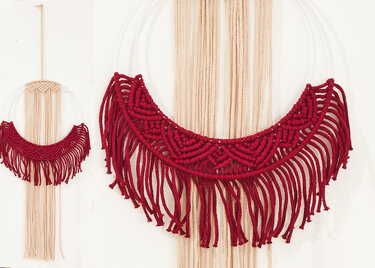 Nahaufnahme roter Makramee-Halbmond mit sichtbaren Knotendetails und Fransen an Metallring
