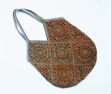 Crocheted shoulder bag of brown and orange granny squares with gray trim and straps on a white background.