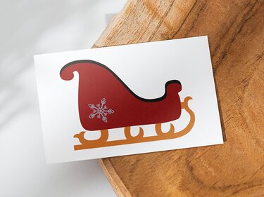 Roter stilisierter Weihnachtsschlitten mit Schneeflocke auf weißer Karte auf Holzuntergrund