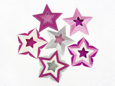 Sechs mehrlagige Papiersterne in Pink, Magenta und Silber mit Glitzer und kleinen Aufhängern
