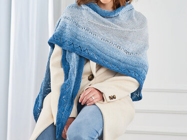 Gestricktes Dreieckstuch in Blau-Grau-Verlauf mit Lochmuster, getragen von einer Person.