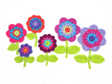 assorted small and large crocheted flower appliques with green stems and leaves on white background