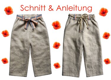 Zwei Kinderhosen aus hellem Leinenoptikstoff; links mit gestreiftem Band, rechts mit Kordelzug; umrahmt von Mohnblumen und dem Schriftzug 'Schnitt & Anleitung'.