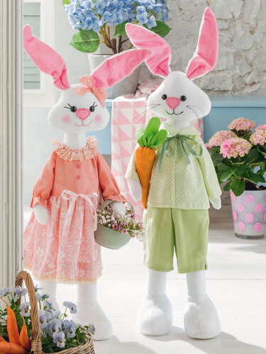 Zwei große, genähte Stoffhasen als Osterdeko: Ein Hasenmädchen im pfirsichfarbenen Kleid mit Körbchen und ein Hasenjunge in Hellgrün mit weicher Karotte.