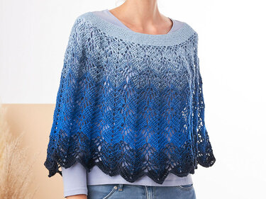 Modell trägt gehäkelten Damenponcho mit Ajourmuster, blauem Farbverlauf und gezacktem Saum