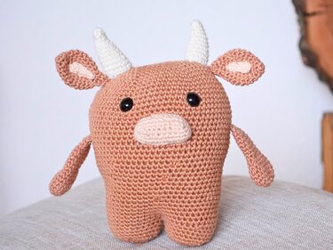 Gehäkelte Amigurumi-Kuh in Braun-Rosé mit weißen Hörnern und schwarzen Augen