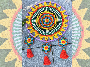 Gehäkelter Mandala-Traumfänger mit konzentrischen Mustern auf lila Ring und drei blütenförmigen Anhängern mit orangen Quasten