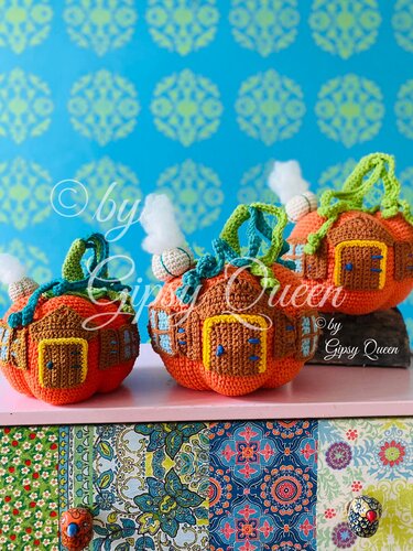 Drei handgehäkelte orange Kürbishäuschen mit liebevollen Details.