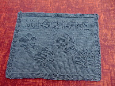 Blue-grey knitted pet mat with paw print motifs and raised lettering