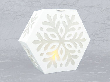 Weiße sechseckige Papier-Lichtbox mit Schneeflocken-Ausschnitten und warmem Licht