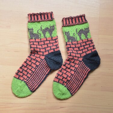 Paar gestrickter Socken mit Katzenmotiv, Ziegelmuster, grüner Spitze und dunkelgrauer Ferse