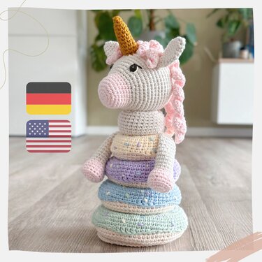 Amigurumi unicorn head on top of removable pastel crochet rings stacked on a wooden floor