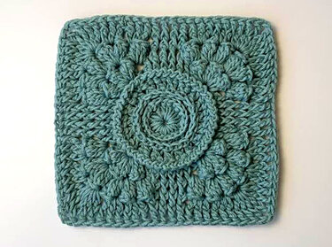 Gehäkeltes Granny Square in Blaugrün mit erhabener Kreisblüte und sichtbarer Maschenstruktur
