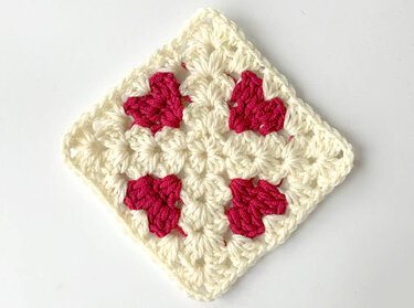 Quadratisches gehäkeltes Granny Square in Creme mit vier pinken Herzmotiven