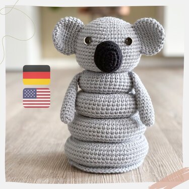 Gehäkelter grauer Koala-Stapelturm mit schwarzer Nase auf hellem Holzboden