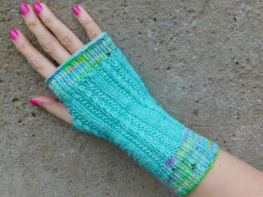 Hand mit türkis gestrickter, fingerloser Armstulpe mit Daumenöffnung und mehrfarbigem Rand