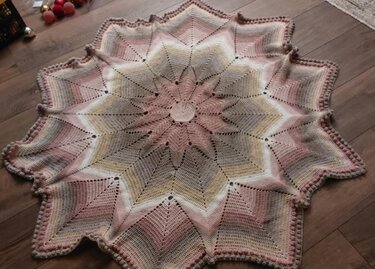 Gehäkelte sternförmige Decke in Rosa, Creme, Beige und Grau mit Farbverlauf auf Holzboden