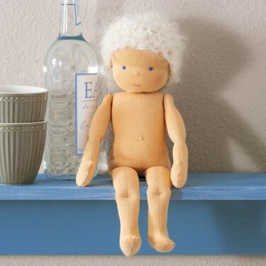 Sitzende weiche Stoffpuppe mit weißem Lockenhaar auf einem blauen Regal