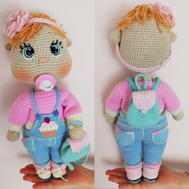 Front and back views of a crochet amigurumi doll wearing blue cupcake overalls, pink sweater, pacifier, floral headband and small mint backpack