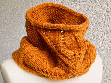 Gestrickter Loop-Schal in Rostorange mit Ajour- und Zopfmuster auf Schneiderpuppe