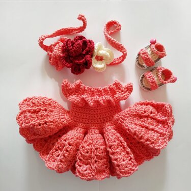 Korallenfarbenes gehäkeltes Puppenkleid mit Rüschen, Blumenstirnband und kleinen Sandalen