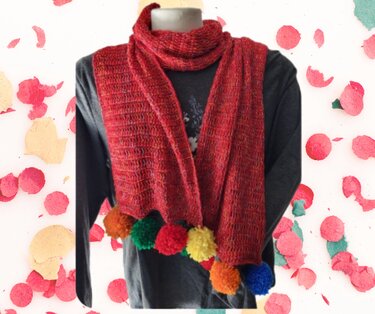 Red crocheted scarf with orange, green, yellow, blue and red pom-poms on a mannequin.