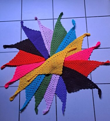 Fan of multicolored triangular crocheted scarves on a tiled floor