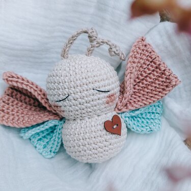 Gehäkelte Figur mit rosa- und türkisen Flügeln, Holzherz und Aufhängeschlaufe