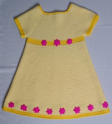 Gelbes gehäkeltes Kinderkleid mit kurzen Ärmeln, pinken Blumenapplikationen und gelben Abschlüssen