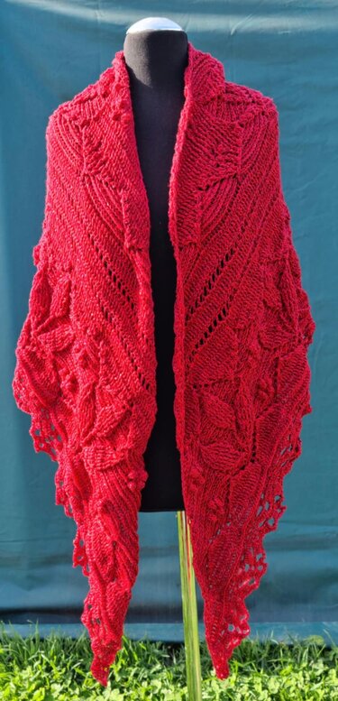 Deep red triangular crochet shawl with leaf motifs draped on a black dress form