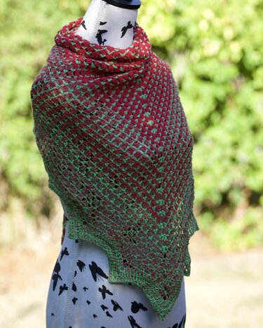 Gehäkeltes Dreieckstuch in Rot und Grün mit luftiger Lochstruktur auf einer Schneiderpuppe