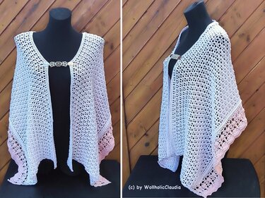 Gehäkelte weiße Stola mit Spitzenrand und Brosche auf schwarzem Mannequin