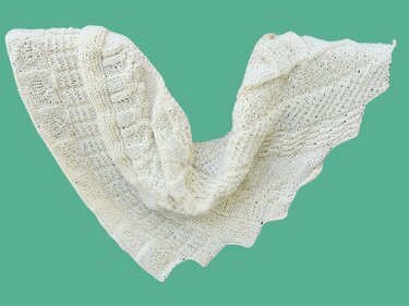 Hellcremiges Drachenschwanz-Stricktuch mit zwei klar unterscheidbaren Mustern: Rauten und Wellen.