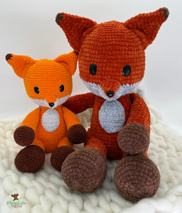 Zwei gehäkelte Amigurumi-Füchse, groß und klein, orange mit hellen Bäuchen und braunen Pfoten