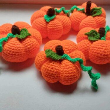 Orangene gehäkelte Mini-Kürbisse mit braunen Stielen und grünen Ranken