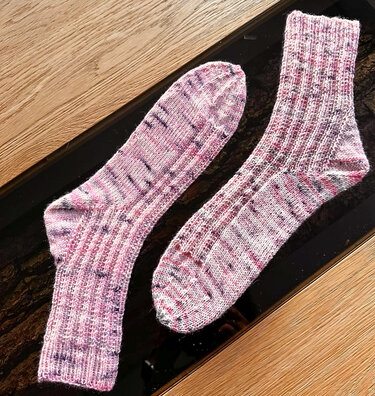 Zwei Stricksocken mit Rippenbündchen, abgerundeter Spitze und meliertem Garn