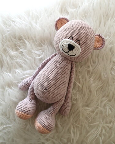 Gehäkelter Amigurumi-Teddybär in Pastell auf weißem Fell