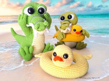 Gehäkelte Amigurumi-Krokodile und Entchen mit Schwimmringen am Sandstrand