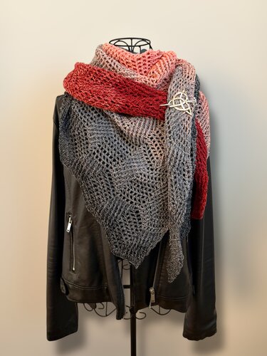 Gehäkeltes Dreieckstuch Rot-Grau mit offenem Muster und keltischer Nadel auf schwarzer Lederjacke