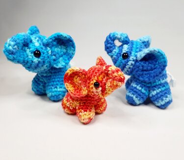 Drei gehäkelte Mini-Elefanten in Blau und Orange, einer mit Schlaufe zum Befestigen