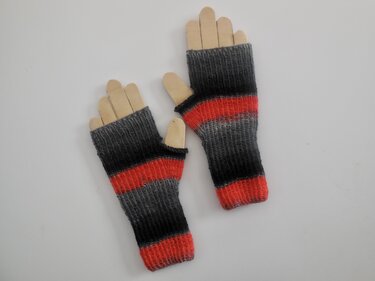 Gestrickte, fingerlose Handschuhe mit grauen, schwarzen und roten Streifen auf Holzhandformen.