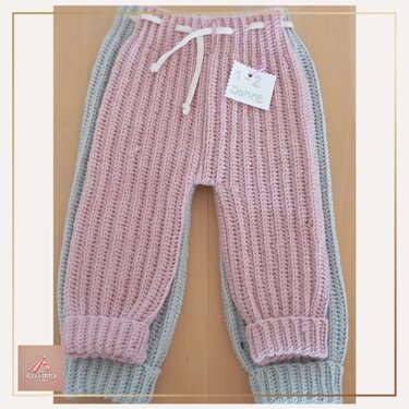 zwei gehäkelte Kleinkinderhosen in Rosé und Grau übereinander, mit Kordelzug und Umschlagbündchen