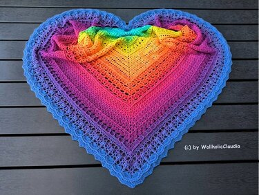 Gehäkeltes Dreieckstuch mit Loch- und Muschelmuster im abgestuften Regenbogenverlauf, flach ausgelegt