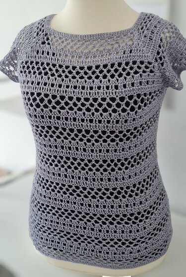 Lavendelfarbener kurzärmeliger Häkelpullover mit Lochmuster auf Schaufensterpuppe, dunkles Untertop sichtbar