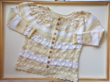 Gestrickte Babyjacke in Creme-Gelb mit Ajourblättern am Kragen, Herz-Ajourstreifen und Knopfleiste