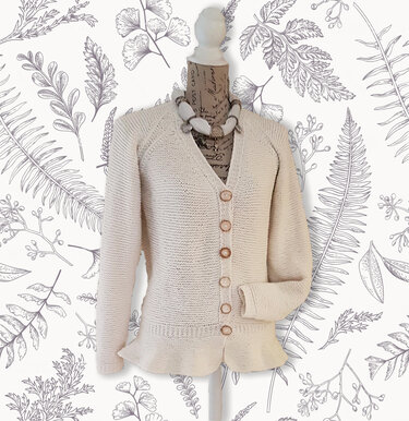 Cream knitted V-neck cardigan with raglan-style sleeves, six brown buttons and a ruffled hem on a mannequin.