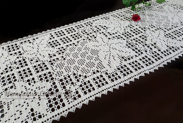 Weißer gehäkelter Tischläufer mit filigranem Spitzenmuster und einer roten Rose auf dunklem Hintergrund
